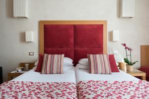 two beds in a hotel room with a red headboard at Hotel Perseo in Florence