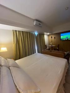 a bedroom with a large white bed and a couch at Flat Tropical Hotel Com Varanda Vista Espetacular in Manaus +14 photos