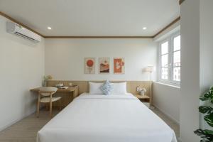 a bedroom with a large white bed and a desk at KOA Apart Hotel Phu Quoc in Phú Quốc