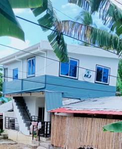 a white house with blue windows on top of it at MJ's Guesthouse in Tubod