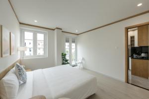 a white bedroom with a bed and a couch at KOA Apart Hotel Phu Quoc in Phú Quốc