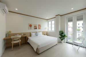 a bedroom with a white bed and a desk at KOA Apart Hotel Phu Quoc in Phú Quốc