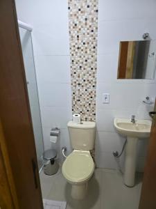 a white bathroom with a toilet and a sink at Pousada Alvorada in Engenheiro Coelho