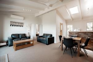 a living room with a table and leather furniture at Beacon Point Ocean View Villas in Apollo Bay