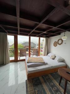 a bedroom with a bed and a large window at Cottage Linggayoni Dieng in Diyeng