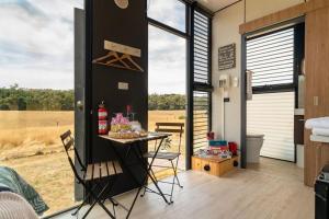 a room with a table and chairs in a tiny house at Tiny Divine Farmstay by Tiny Away in Korweinguboora