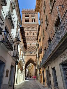 an alley with a tall clock tower in the background at Hostal Casa Amalia in Teruel +14 photos