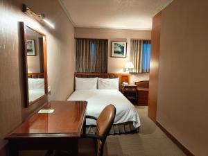 a hotel room with a bed and a desk at First Hotel in Taipei