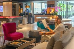 a man sitting on a couch reading a book in a store at Pan Pacific Serviced Suites Beach Road, Singapore in Singapore +39 photos