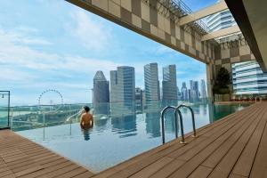 a man sitting in a swimming pool with a view of a city at Pan Pacific Serviced Suites Beach Road, Singapore in Singapore