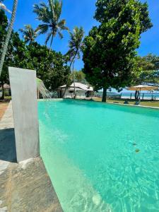 a swimming pool with turquoise water and palm trees at Lido Dikwella in Dickwella