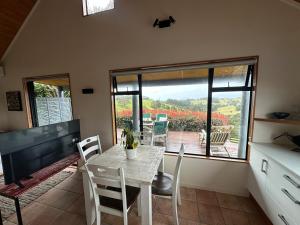 a dining room with a table and chairs and a large window at Matapouri Sanctuary Apartment in Matapouri +5 photos