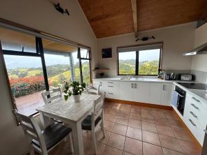 a kitchen with a table and chairs and a kitchen with windows at Matapouri Sanctuary Apartment in Matapouri