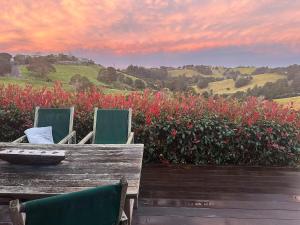 a wooden table and chairs with red flowers at Matapouri Sanctuary Apartment in Matapouri