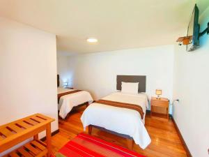a bedroom with two beds and a red rug at Cusco - Flor de Loto in Cusco