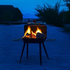 a grill with a fire in it at night at PULAU LIMA Resort in Serang