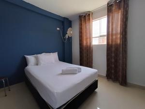 a bedroom with a large white bed with a blue wall at Barlovento Business Hotel in Piura +15 photos