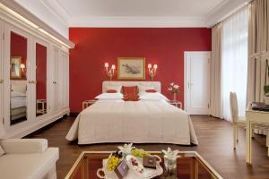 a bedroom with a large bed with red walls at Hotel Europäischer Hof Heidelberg in Heidelberg