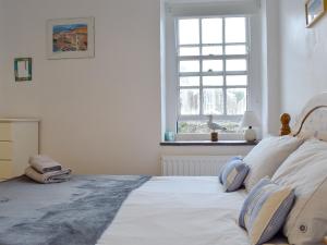 a bedroom with a white bed with pillows and a window at Windjammer Cottage in Swanage