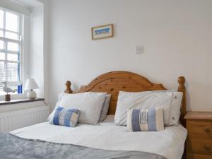 a bed with white sheets and blue and white pillows at Windjammer Cottage in Swanage