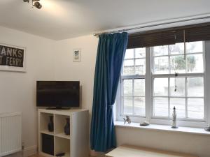 a living room with a large window with blue curtains at Windjammer Cottage in Swanage