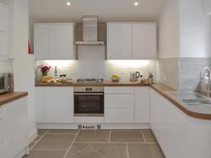 a white kitchen with white cabinets and a sink at Samphire Lodge in Brixham