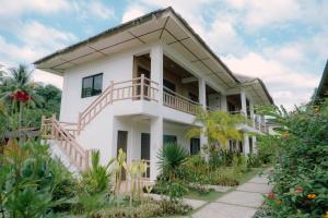 a white house with a balcony and plants at Sevens Hideaway Beach Resort in Siaton