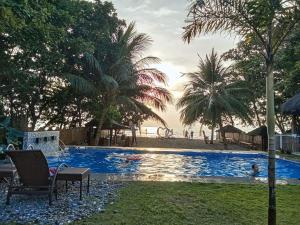 a swimming pool with palm trees and people in the background at Sevens Hideaway Beach Resort in Siaton