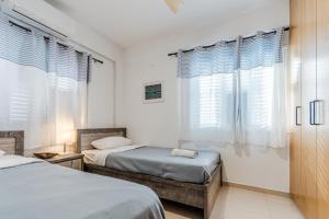 two beds in a room with white walls and windows at Seaview Sanctuary House in Larnaca