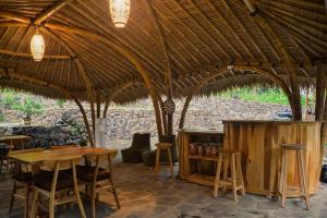 a room with a table and chairs under a straw roof at Beda gaya ecolodge Rangsot 3 in Tanjung