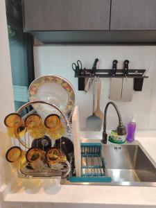 a kitchen sink with dishes in a dish drying rack at CeeJay Suites in Penampang