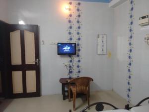 um quarto com uma mesa e uma televisão na parede em New Regency em Chennai