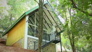 a house with a balcony in the woods at Ranthilaka Villas in Kandy