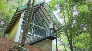 a house in the woods with a balcony at Ranthilaka Villas in Kandy
