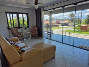 a living room with a couch and large glass windows at Quarto casal Nereidas bwc compartilhado in Guaratuba