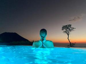 a person sitting in a swimming pool watching the sunset at Sueño Verde EcoVilla in Cerro Verde +25 photos