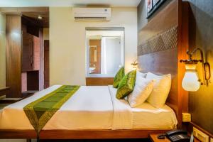 1 dormitorio con 1 cama grande con almohadas amarillas y verdes en Hotel Sonia CIDCO en Aurangabad