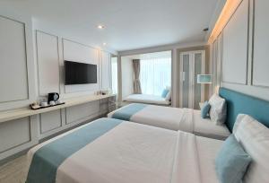 a hotel room with two beds and a television at The Bloc Hotel Phuket in Patong Beach