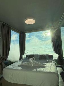 a bedroom with a bed with a large window at หลงใหล ภูทับเบิก in Ban Maeo Thap Boek