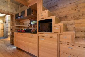a kitchen with wooden walls and cabinets with a tv at Mazot du Mont-Blanc w/View, Terrace & Stove, (Sleeps 4) - Happy Rentals in Chamonix