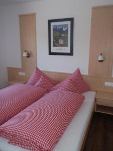 a bedroom with two beds with red and white sheets at Landhaus Alpenjäger in Hainzenberg