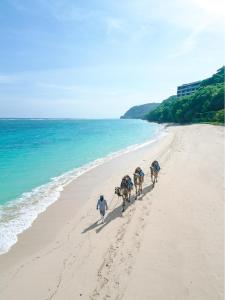 a group of people riding horses on the beach at Samabe Bali Suites & Villas in Nusa Dua
