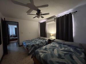 a bedroom with two beds and a ceiling fan at Comfortable apartment 10 min BBVA Stadium - Wi-fi Parking SmartTV & AC in Monterrey