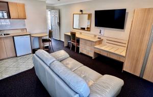 a living room with a couch and a flat screen tv at Colonial Terrace Motor Inn in Raymond Terrace