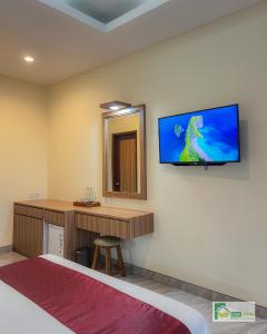 a hotel room with a bed and a television on the wall at Casa Verde Guest House in Sempidi