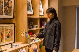a woman standing in front of a shelf in a store at Sumu Ueno East in Tokyo