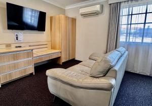 a living room with a couch and a flat screen tv at Colonial Terrace Motor Inn in Raymond Terrace
