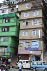 un edificio alto con coches estacionados frente a él en Hotel Kasturi, en Gangtok