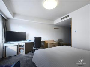 a hotel room with a bed and a desk with a television at Daiwa Roynet Hotel Hakata-Gion in Fukuoka