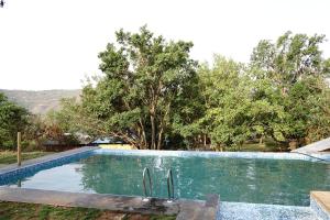 a swimming pool in a yard with trees at Avanti Kalagram Hill Top Resort, Mulshi in Kolvan